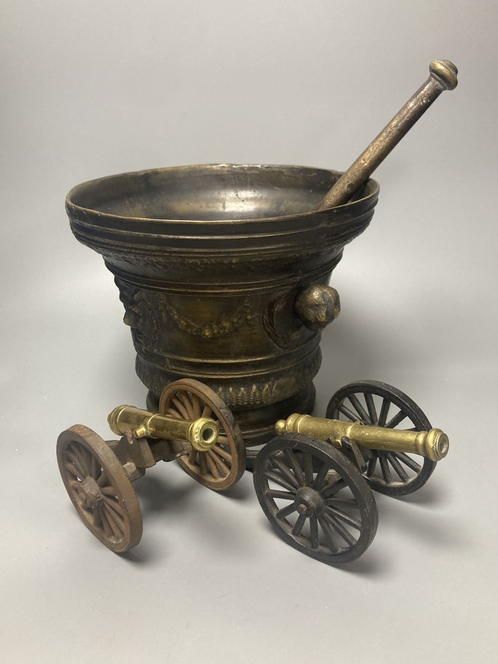 A large bronze mortar and pestle, bearing mock date 1630, 25cm diameter, and two iron and brass canon models